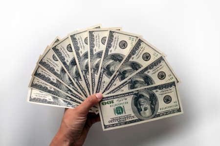 Male hand holds few hundreds US dollars on white background: 100 usd currency banknotes. Inflation, business, economics and finance theme.の写真素材