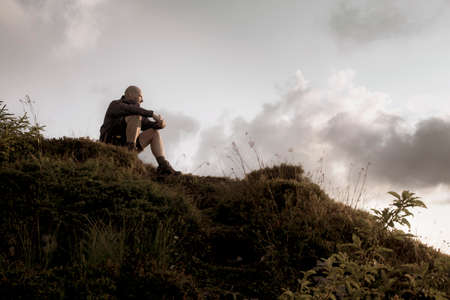hiker rests on top of the mountain in the colors of the setting sunの写真素材