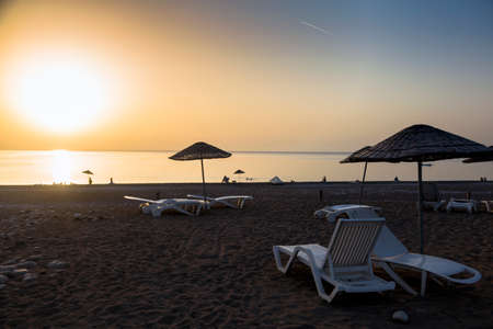 White tourist sunbeds on the beach featuring a mix of sand & small pebbles in the Mediterranean coastの写真素材