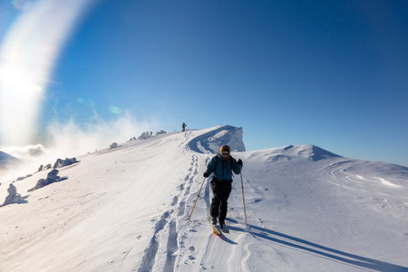 A group of ski mountaineers climbs to the top of a snow-capped mountain on a backcountry terrain, adrenaline outdoor winter adventuresの写真素材