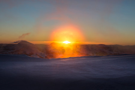Bright orange sunrise of the sun disk in the snowy mountains. Marmarosy, The Carpathian mountain range. Marmarosy, The Carpathian mountains. Winter mountains landscape outdoor conceptの写真素材