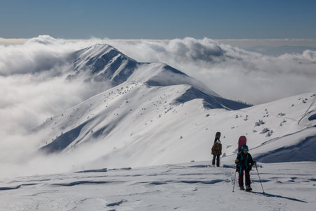 An active female freerider with a snowboard going to the top of the mount in a backcountry alpine mountain terrainの写真素材