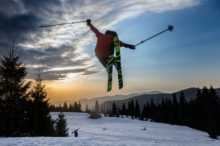 Marmaros, The Carpathians, UKRAINE - March 15 2021: freestyle extreme skier jumping from kicker in snowy mountains at orange sunset, an adrenaline outdoor adventuresのeditorial素材