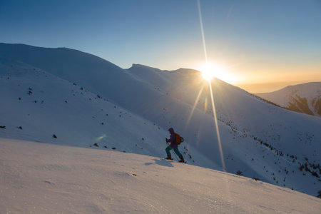 A skier climbs to the top in the rays of the morning sun, active recreation in the backcountryの写真素材