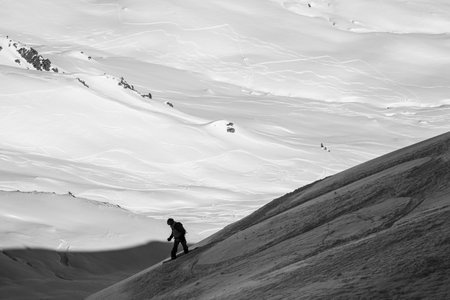 black and white photo of freerider snowboarder riding down snow-covered slope, winter freeride...