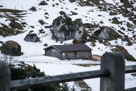 Kaltenbach âHochfugen, Austria - 9 Jan, 2020: An old farmhouse under a large stone cliffの写真素材