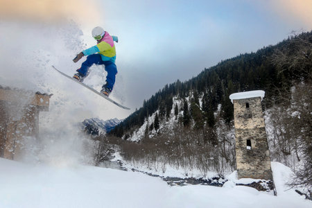 A snowboarder makes a jump over the historical Svan tower in Mestia, Georgia, Love Towerの写真素材