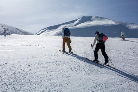 The rugged beauty of the winter mountains serves as the perfect backdrop for a group of skiers, who eagerly climb upwards, their eyes fixed on the pristine slopes aheadの写真素材