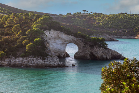 A rock formation in the water with a small island in the background. The rocky coast of the Adriatic Sea, Italyの写真素材