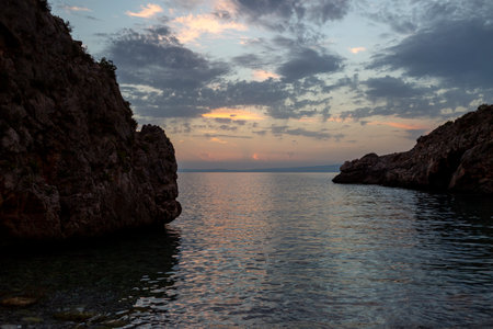 Tranquil Mediterranean Shore with Stunning Sunset over Rocky Coastline.の写真素材