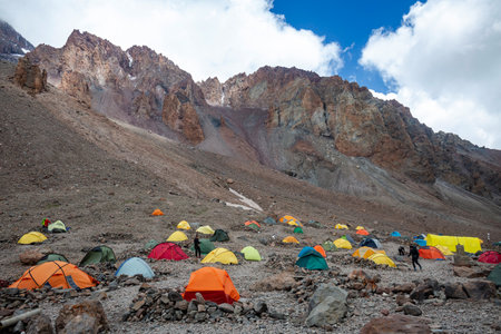 Vibrant Base Camp: A colorful array of tents sprawls across the rocky terrain, nestled beneath the towering mountain.の写真素材