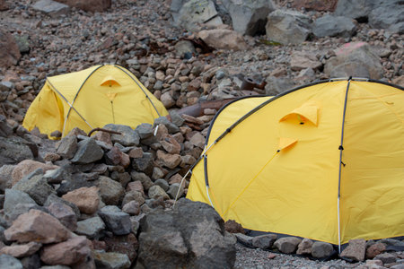 Vibrant Base Camp: A colorful array of tents sprawls across the rocky terrain, nestled beneath the towering mountain.の写真素材