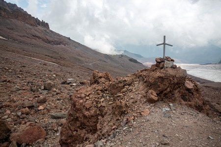 A winding path leads up a steep mountain. A solitary cross stands on a rocky peak. A rugged and...