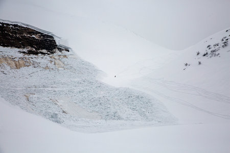 A skier takes on the risk: A lone figure challenges the aftermath of an avalanche, skiing through...