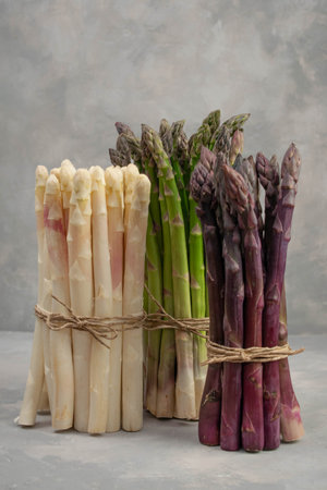 Three bunches of different fresh asparagus isolated on grey. Purple white and green asparagus.の写真素材