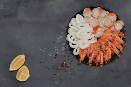 Plate of fresh mixed seafood isolated on gray background. Shrimp, squid rings, scallop.の写真素材