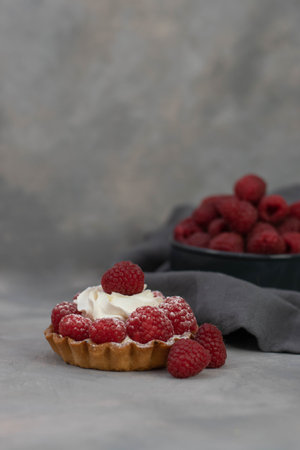 A delicious dessert for the whole family and easy diet, raspberry basket of unleavened dough with a gentle sprinkle with powdered sugar. Grey background.の写真素材
