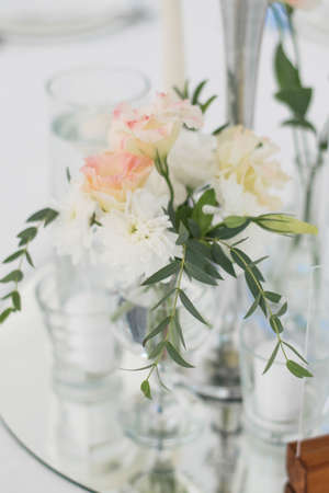 Close-up of a wedding dinner table at reception. Fresh flowers and candles on mirros plate. Wedding decorations. Table centerpieces.の写真素材