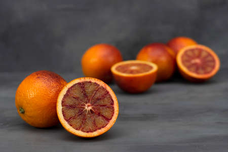 Blood orange on a table. Juicy red fruit texture close up. Gray background with copy space. Healthy...