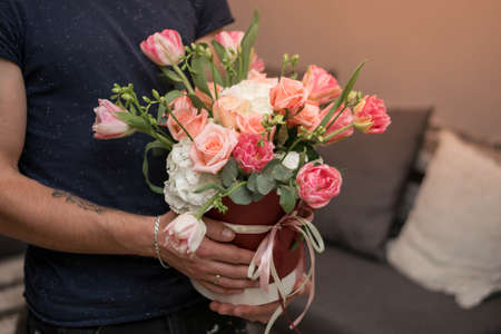 Male hands holding beautiful floral arrangement in a hat box