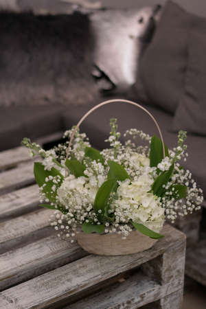 Beautiful flowers in a basket on white wooden table.の写真素材