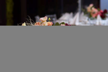 White tablecloths with clear vases and colourful flowers arrangements. Golden colored plates, peavh napkins, table numbers and mirror centerpieces. Wedding day.の写真素材