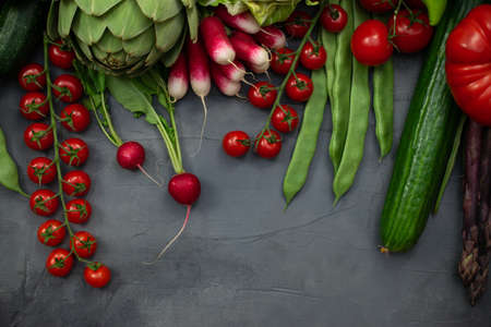 Different organic vegetables - asparagus, tomatoes cherry, avocado, artichoke, pepper, lime, redish, cauliflowerm, green beans, cucumber on gray background.の写真素材