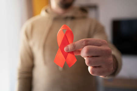 Caucasian man holding red aids ribbon. Hiv aids symbol. Hiv control concept.の写真素材