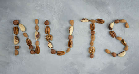 the word nuts from a mixture of nuts on a light gray background. Bio nuts