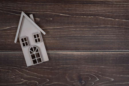 Wooden house on a wooden background. Buying a house with a young family. Affordable housing. banner. Family psychology, strong relations.の写真素材