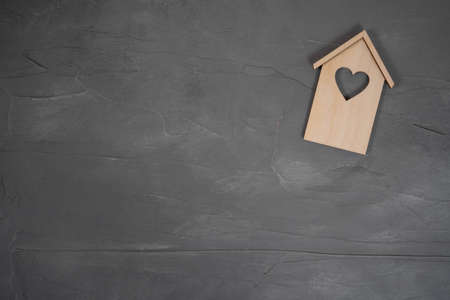 Wooden house on a gray stone background. Buying a house with a young family. Affordable housing....