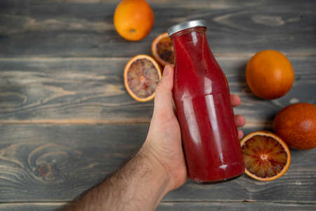 Bottle of blood orange juice with halved fruit on wooden tableの写真素材