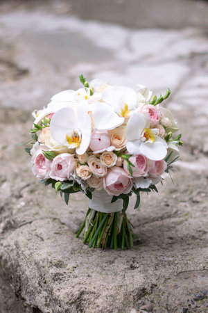 Wedding bouquet on gray stone background. Bridal bouquet composed of roses, freesia, peony and phalaenopsis orchids.の写真素材