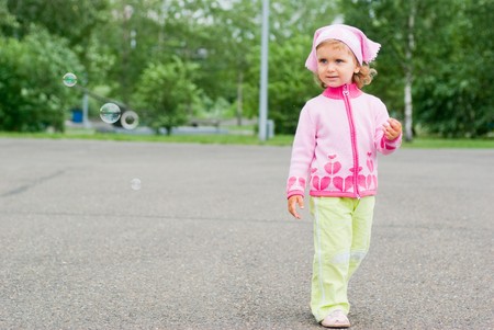 girl running next to the bubbles in the parkの写真素材