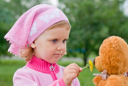 A little girl gives her cub sniff a dandelionの写真素材