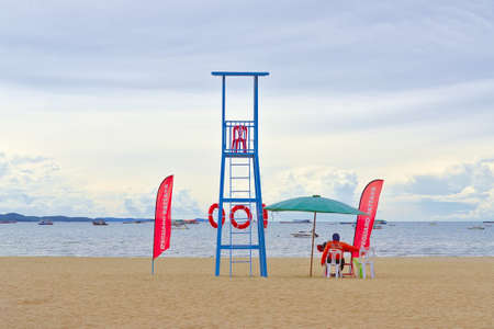 An on-duty Lifeguard is keenly watching on few local tourists swimming around the long stretch beach front.の写真素材