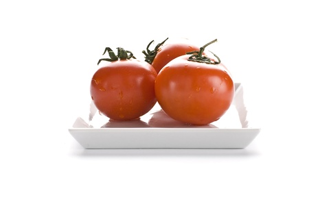 three red tomatoes on a white dishの写真素材