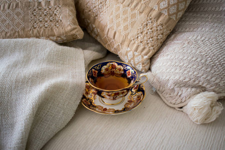 Cup of tea in cozy winter mood environment with white blanket and cushionsの写真素材