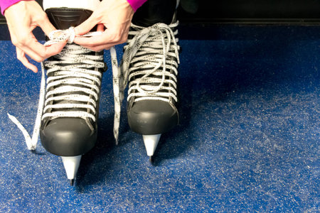Woman tying skate laces in locker roomの写真素材