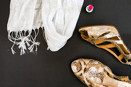 Top view of woman beauty accessories heels, lipstick, scarf in black background with text spaceの写真素材