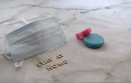 Front view of surgical mask with stay at home sign and soap over marbled background with copy spaceの写真素材