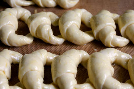 Ready to bake, raw Argentine croissants, medialunas de Manteca over silicon pastry mat backgroundの写真素材