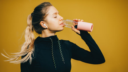 Attractive caucasian girl on yellow isolated background with wireless headphones in sport suit make...
