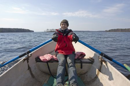 Young smiling woman rowing on boat on a big forest lake in Karelia