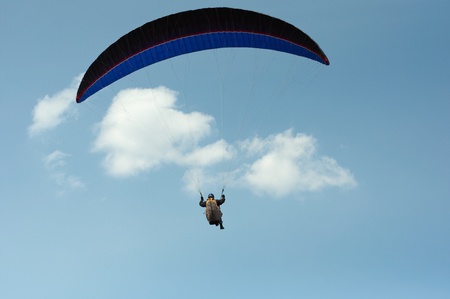 paraglider pilot flying against the blue sky