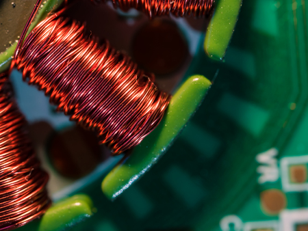 Red copper wire spools on a green printed circuit board