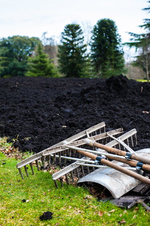 Gardening tools lying on a spring green lawn with freshly digged compostの写真素材