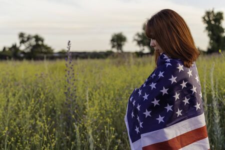 Young excited woman with the United States flag enjoying sunset in nature. July 4 independence day of the united statesの写真素材