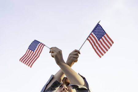 copy space. caucasian woman hand with American swaying flag on the blue sky. isolated. America. USA. Concept. July 4 United States.の写真素材