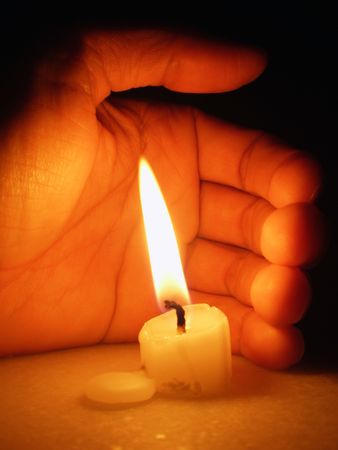 Candle and a hand covering it         の写真素材